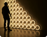 a man standing in front of a wall with a large light