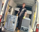 man stading next to washing machine in the back of van