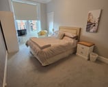 A large bedroom at Gourock Seaview Holiday Let with a kingsize bed and a chair