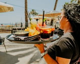 Camarera sirviendo bebidas y nachos en la terraza de Santa Lola Badalona