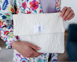 Pochette à rabat blanche ÉTOFÉ en tissu recyclé texturé, faite main en France, tenue par une femme