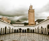 a clock tower in a courtyard with a clock tower in the background