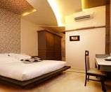 Modern hotel room with a smart TV, desk, and coffee table.