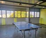 Table tennis area with a table, net, and surrounding floor space.