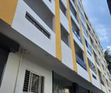 Tall Yellow and white building with lots of rooms and balconys.