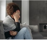 a woman sitting on a couch with her hands on her head