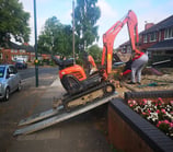 mini digger being loaded into a garden in dudley