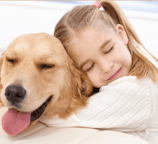 A young girl hugging her golden retriever