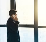 Uomo al cellulare che guarda fuori dalla finestra