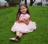 Niña sentada en el pasto sonriendo