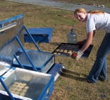 Jenny is taking cookies out of the solar oven