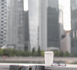 a black tote with a coffee cup on a wall with city buildings in the background