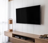 Painel ripado e mobiliário planejado em madeira, trazendo aconchego e elegância para a sala de TV.