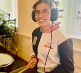 a woman in a white jacket and headphones playing drums