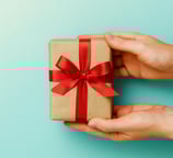 Mãos entregando um presente com laço vermelho, simbolizando oferta gratuita do eBook cristão