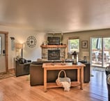 Warm and inviting living room with stone fireplace, flat-screen TV, and access to outdoor deck.