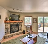 Stone fireplace and cozy lounge area with forest views and walk-out deck at Moose Creek Lodge.