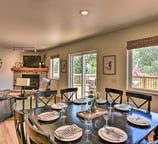 Large dining table set for eight with views of the stone fireplace and walk-out deck.