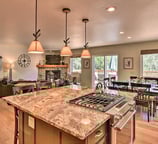  Open-concept kitchen and living room with large granite island, gas range, and fireplace.