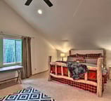 Rustic bedroom with log-frame bed, plaid bedding, and vaulted ceiling.