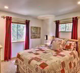 Bright guest bedroom with forest views, red curtains, and queen memory foam bed.