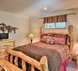Warm and rustic bedroom with log frame bed, flat-screen TV, and woodsy charm.
