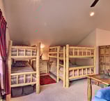 Four twin beds in rustic log bunks tucked into a lofted space.
