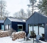 Tiny home pods with firewood stacks in snowy winter setting