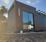 Modern tiny home pod with glass doors and wood siding