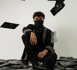 a man in a black shirt and black pants sitting on a pile of black and