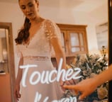 Une femme habillée en robe de mariée touche l'écran tactile du miroir photobooth de pixtoevent