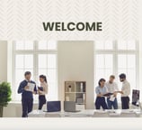 a group of people standing around a desk with a welcome sign