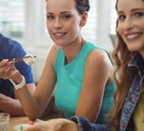 Vrouw zit aan tafel met een bord gezond eten.