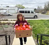 a woman holding a box of food in front of a van