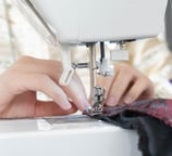 Gros plan sur des mains guidant un tissu sur une machine à coudre