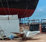 a boat sitting on the ground next to a large boat