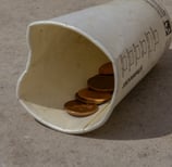 a empty cup on a street with a few coins inside
