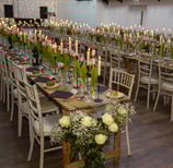 a long table with candles and flowers in a room