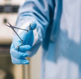a person in a blue glove holding scissors
