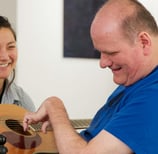 A disabled adult male learning to play the guitar