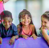 three young children in colorful gym attire are smiling and posing for a picture