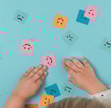 image avec des mains d'enfant jouant avec des images d'émotions