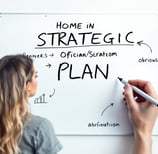 a woman is writing a strategy on a white board