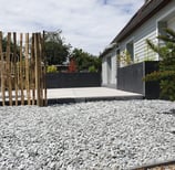 Allée moderne en gravier avec terrasse en dalles et palissade en bois
