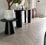 A light oak herringbone floor in a hallway with a step and small tbale