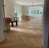 An oak herringbone floor in a living room with a red chair