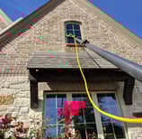 Cleaning a window of a brown brick home with a five stage filtration water pool 