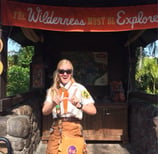 an informal educator in a costume posing in front of a map at Walt Disney World