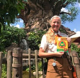 a teacher in a costume is holding a guidebook at Disney's Animal Kingdom in Walt Disney World