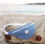 Sac banane ÉTOFÉ en tissu recyclé bleu, fait main sur la Côte d'Azur, posé sur une plage
